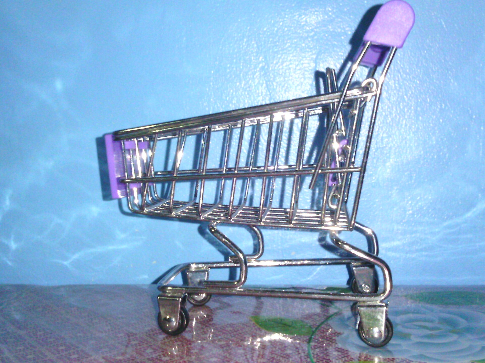 Miniature shopping cart against a blue background